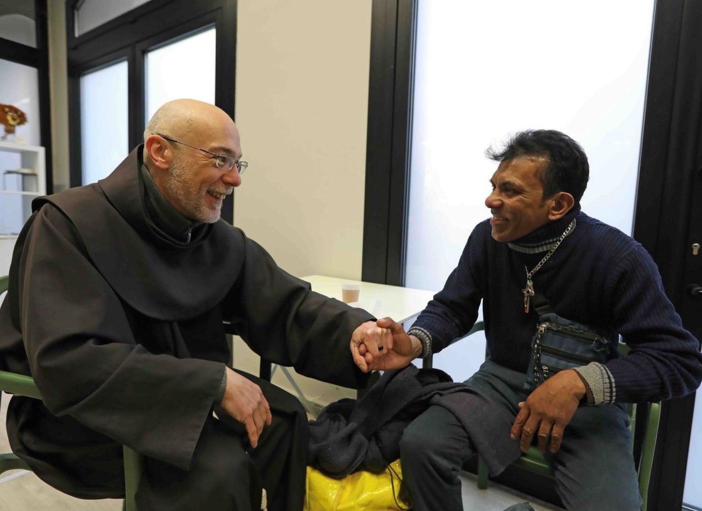 Frate che ascolta un ospite tenendolo per mano